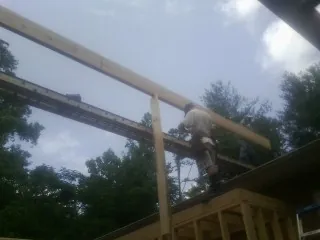 Carpenter setting a ridge beam over a new addition frame — Ice Dam Removal by Roofing Brothers in Beech Bluff