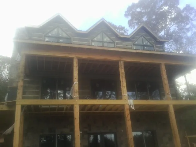 Dormers and porch framing on a large log home under construction — Roof Coating work by our crew in Beech Bluff