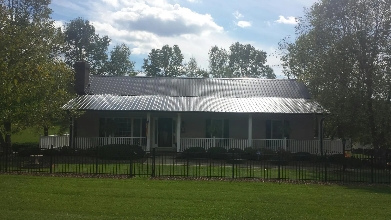 Gray metal roof on a brick ranch with a full width front porch — Gutter Guard Installation work by our crew in Beech Bluff