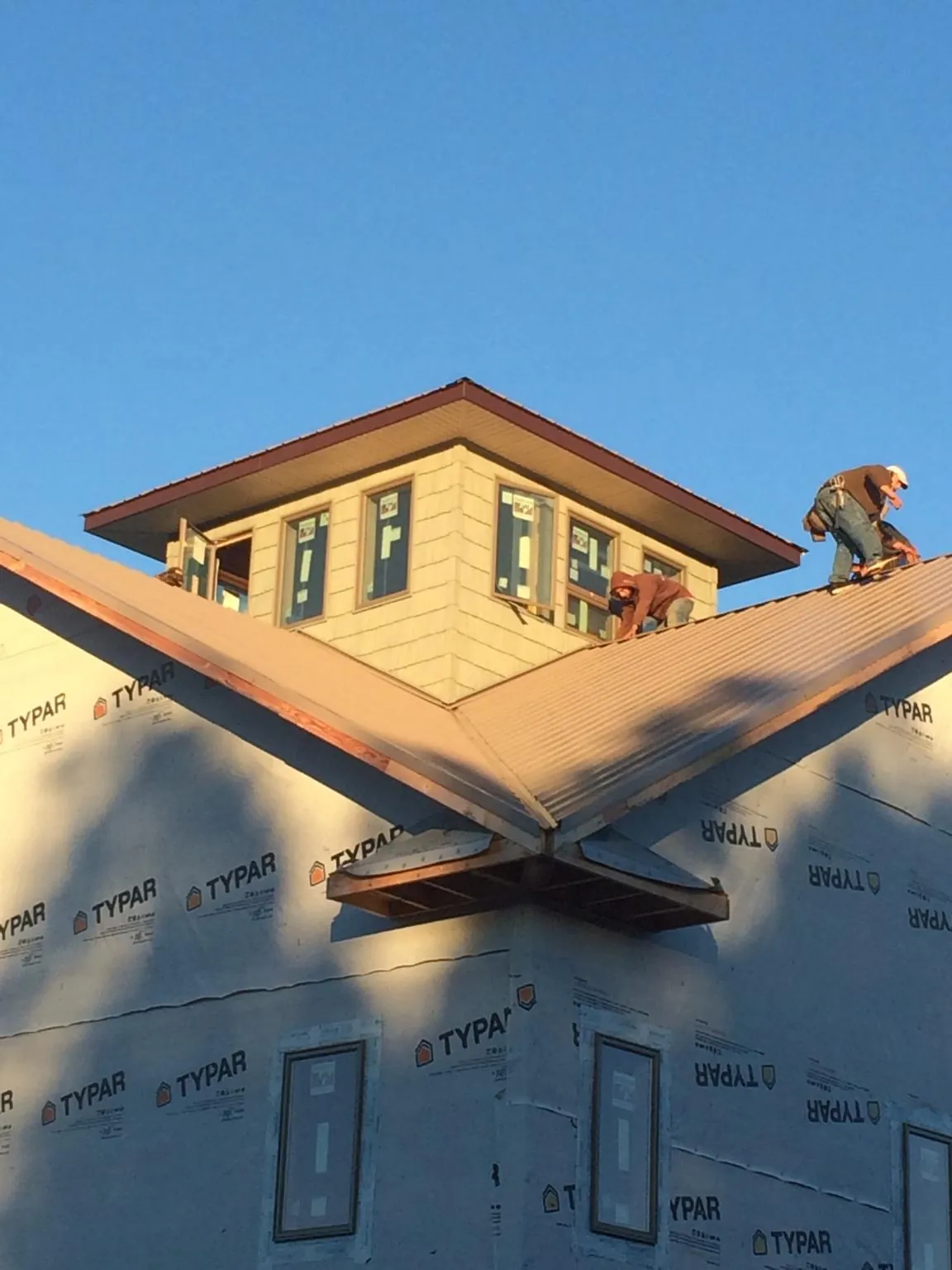 Roofers working around a rooftop cupola on a new metal roof at sunset — Roof Waterproofing in Beech Bluff by Roofing Brothers